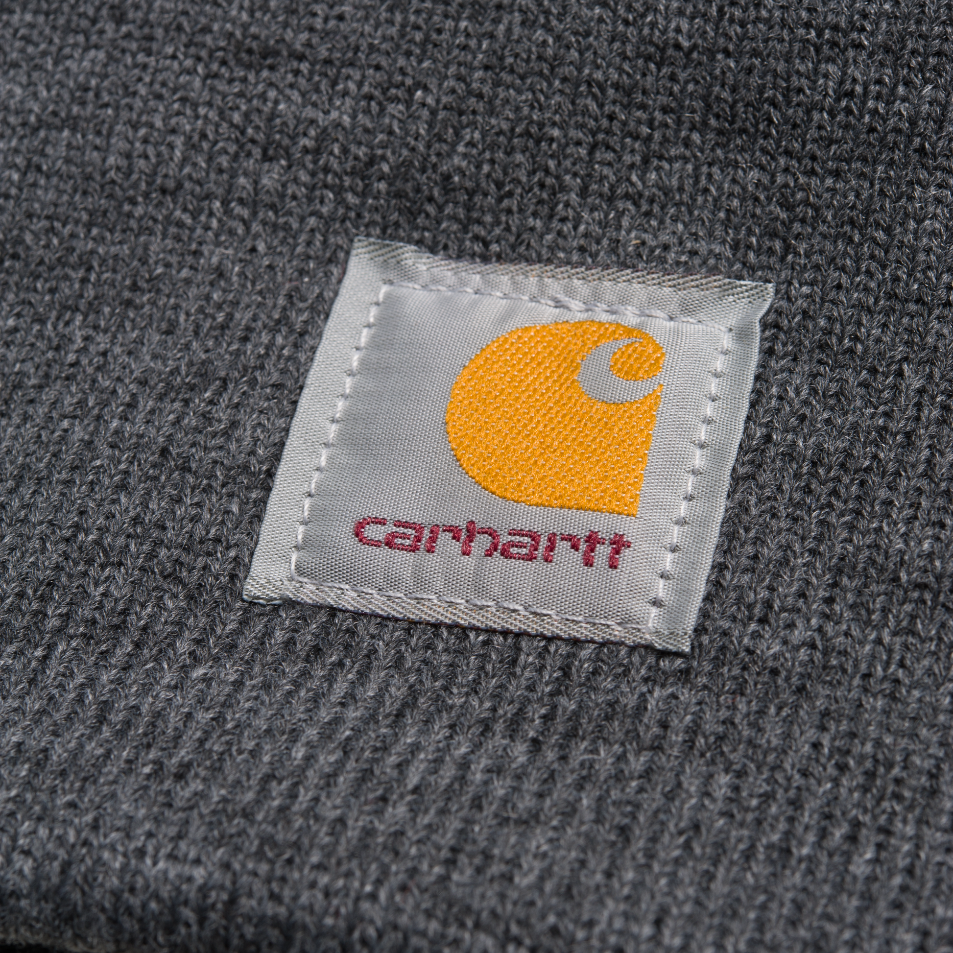 Carhartt WIP Acrylic Watch Hat em Dark Grey Heather. Foto de detalhe do logo na frente.