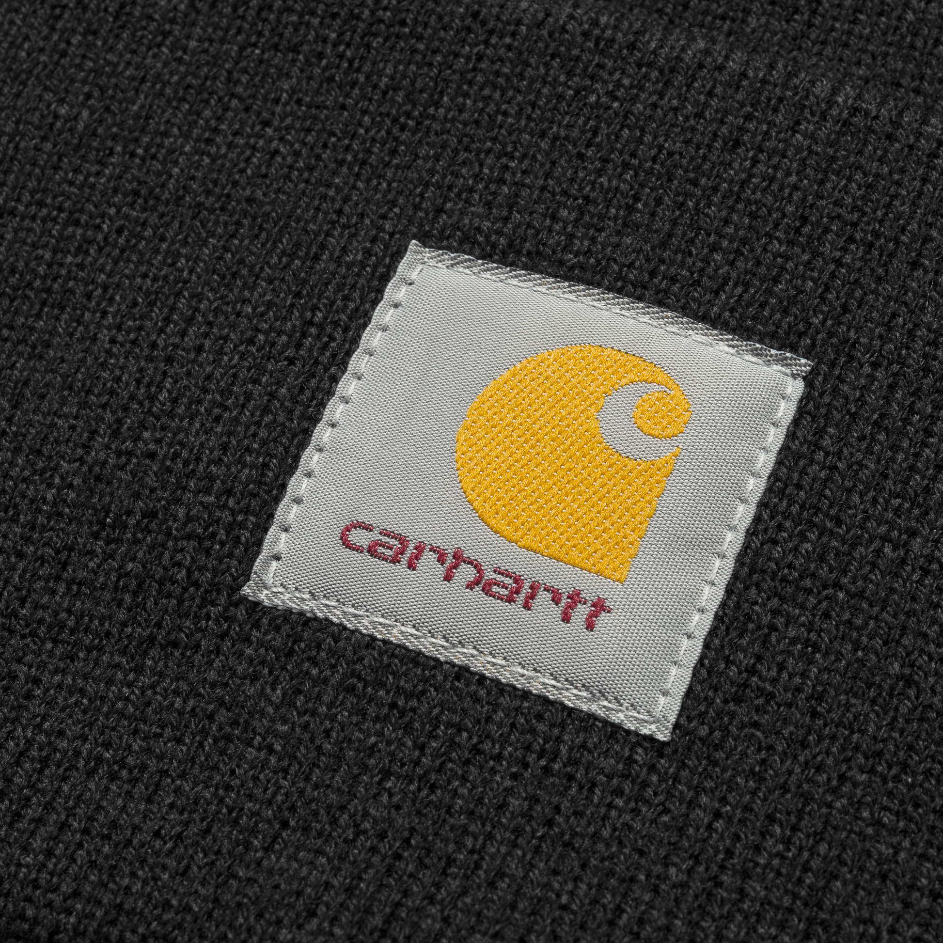 Carhartt WIP Acrylic Watch Hat em preto. Foto de detalhe do logotipo na frente.