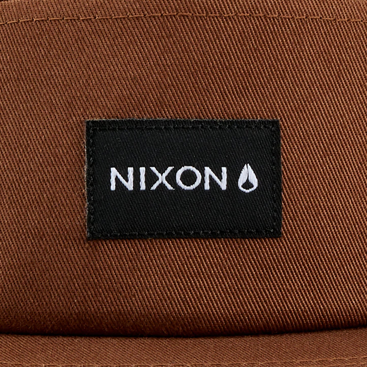 Nixon Mikey Strapback Hat Brown. Foto de detalhe do logotipo na frente.