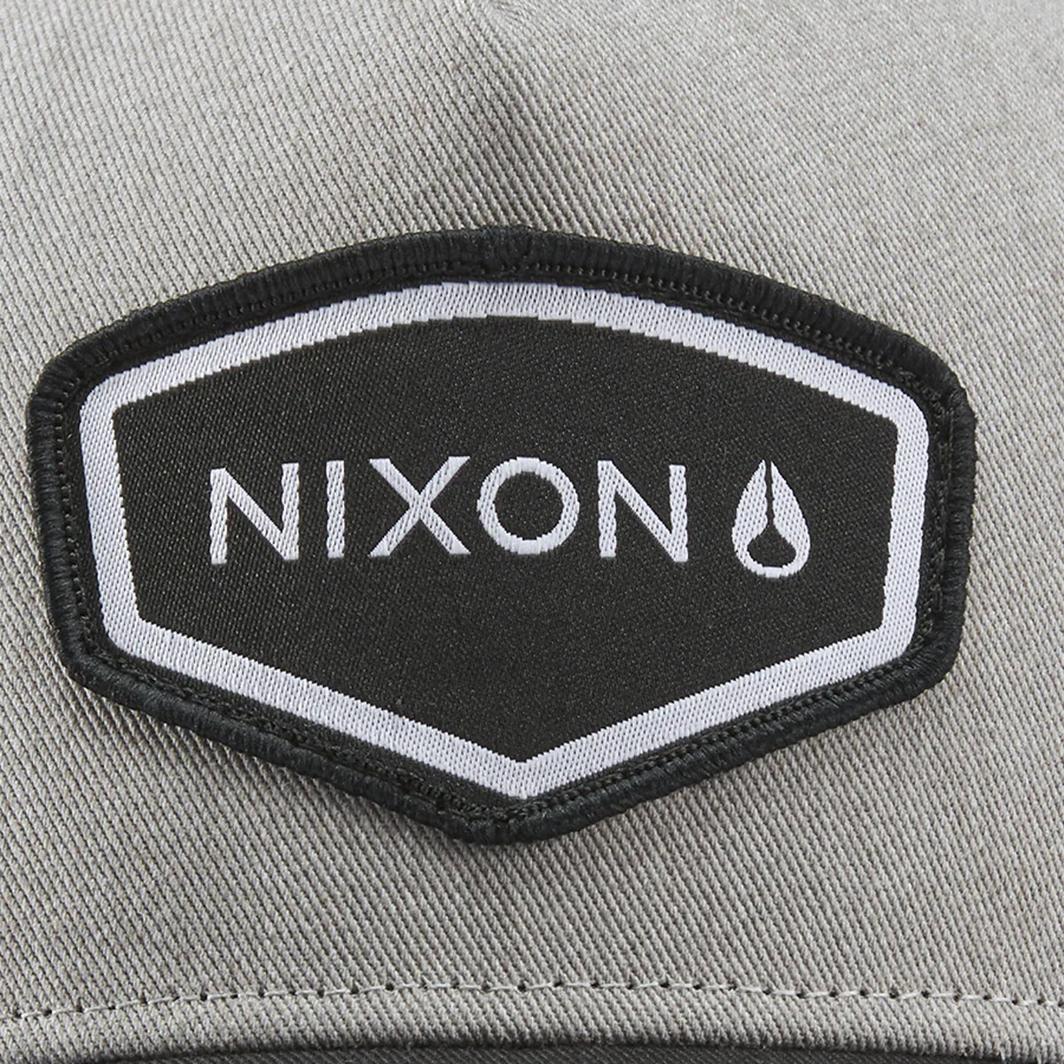 Nixon Watts Snapback Grey Heather/Black. Foto de detalhe do logotipo na frente.