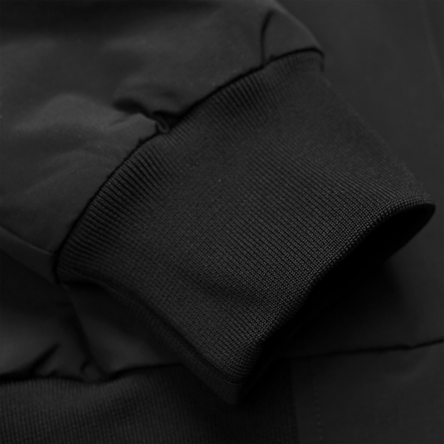 Carhartt WIP Hooded Sail Jacket em preto com logo bordado na frente em branco. Foto de detalhe do punho.